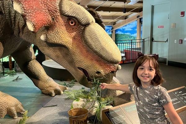 school aged summer campers with an animatronic dinosaur